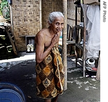 An elderly woman stands next to her temporary shelter nearly one year after an earthquake shuttered the region, 20 May 2007