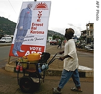 A man passes in a Freetown suburb, a poster for opposition candidate Ernest Bai Koroma, ahead of presidential elections, 06 Aug 2007