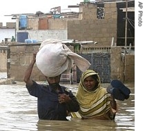 A Pakistani family make their way through a flooded street after a heavy rain on 10 Aug. 2007 in Karachi, Pakistan