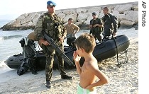 UNIFIL Spanish soldier holding M60 machine gun stands guard near navy divers as Lebanese boy looks on