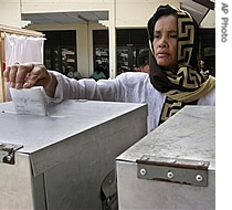 An Acehnese woman casts her ballot at a polling station, 11 Dec 2006 