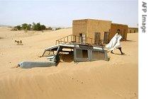 A man walks by a jeep covered by sand in the village of Boumdeid, near Kiffa in Mauritania (08 Jun 2002)
