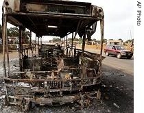 Remains of a bus that was burnt by demonstrators are seen as people drive past in Conakry, Guinea <br/>(File photo - 25 jan 2007)