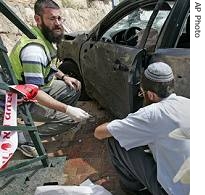 Israeli rescue workers are seen next to a car hit by a Qassam rocket fired by Palestinian militants from Gaza in the southern Israeli town of Sderot, 27 May 2007