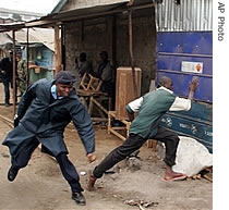 A police officer chase a man accused of throwing stones at police as officials disconnected illegal electricity connections in the Mathare slum in Nairobi, Kenya, 19 July 2007